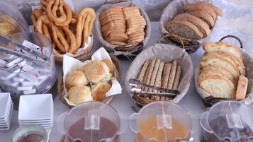 A variety of baked goods including pretzels, bread rolls, and sliced bread, along with several containers of sauces.
