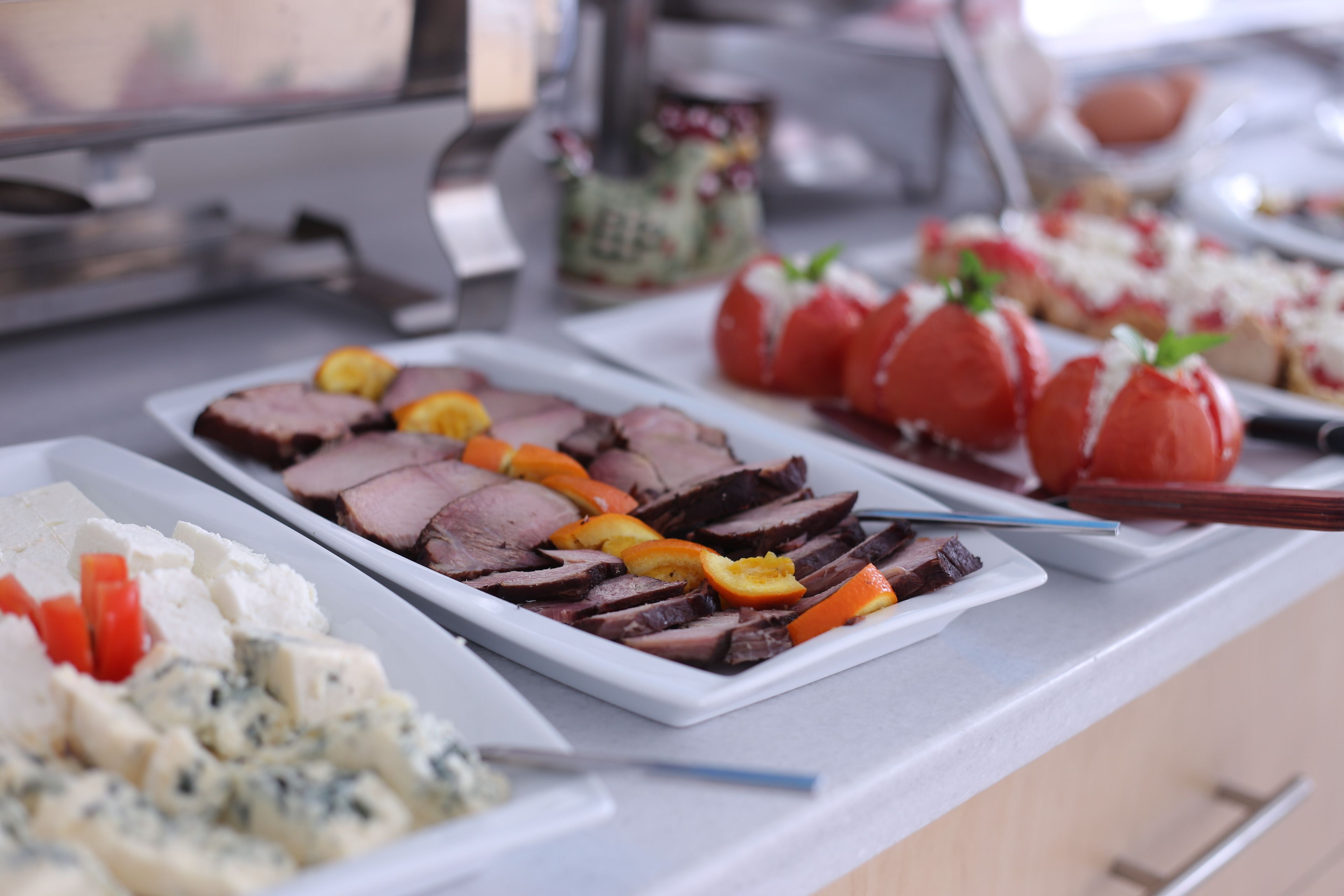 Buffet com diversos alimentos, incluindo carne fatiada, queijo e legumes.