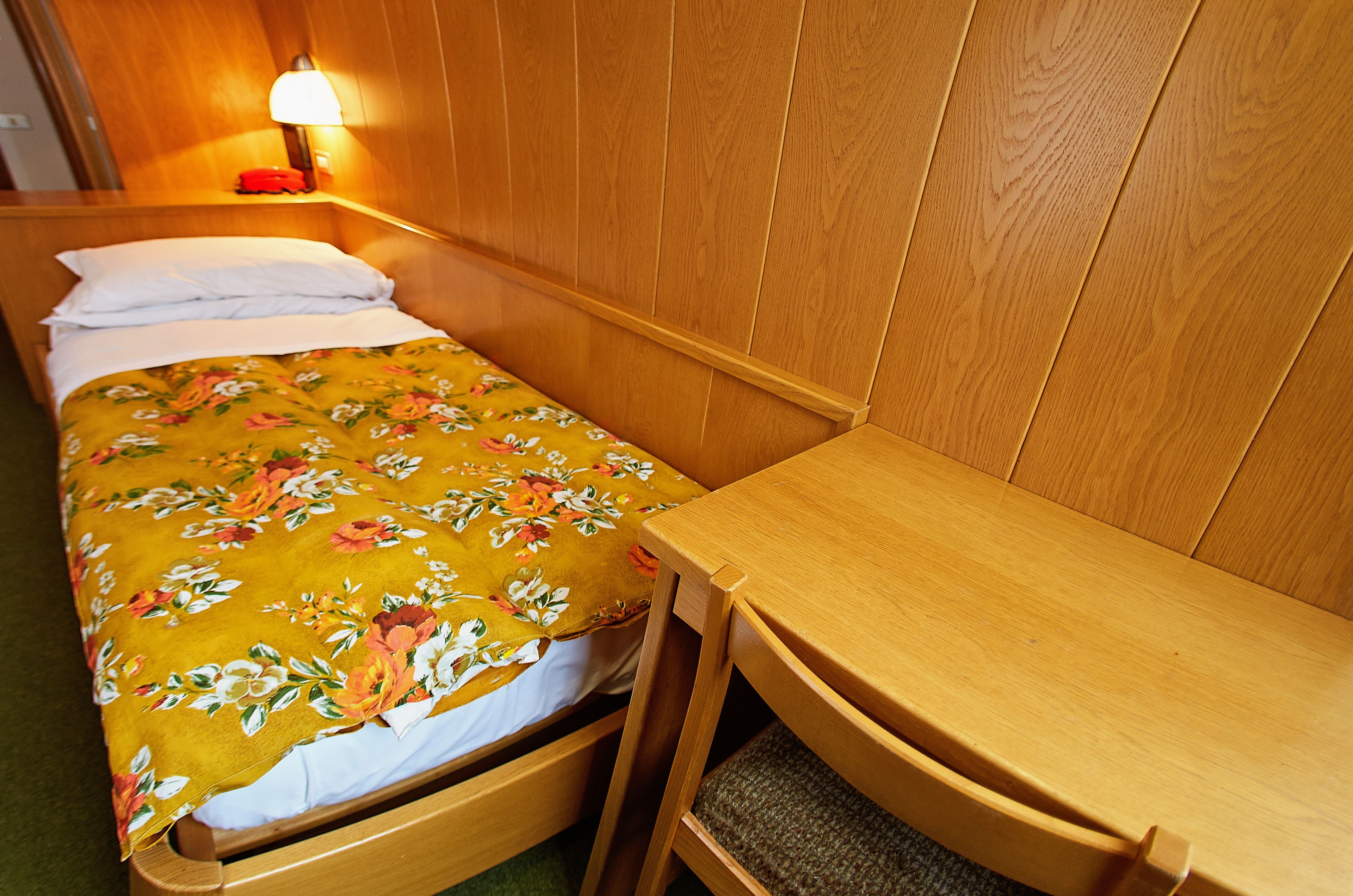 Una cama individual con una colcha estampada, una mesita de noche y una lámpara.