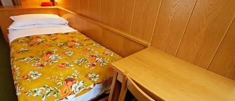 Una cama individual con una colcha estampada, una mesita de noche y una lámpara.