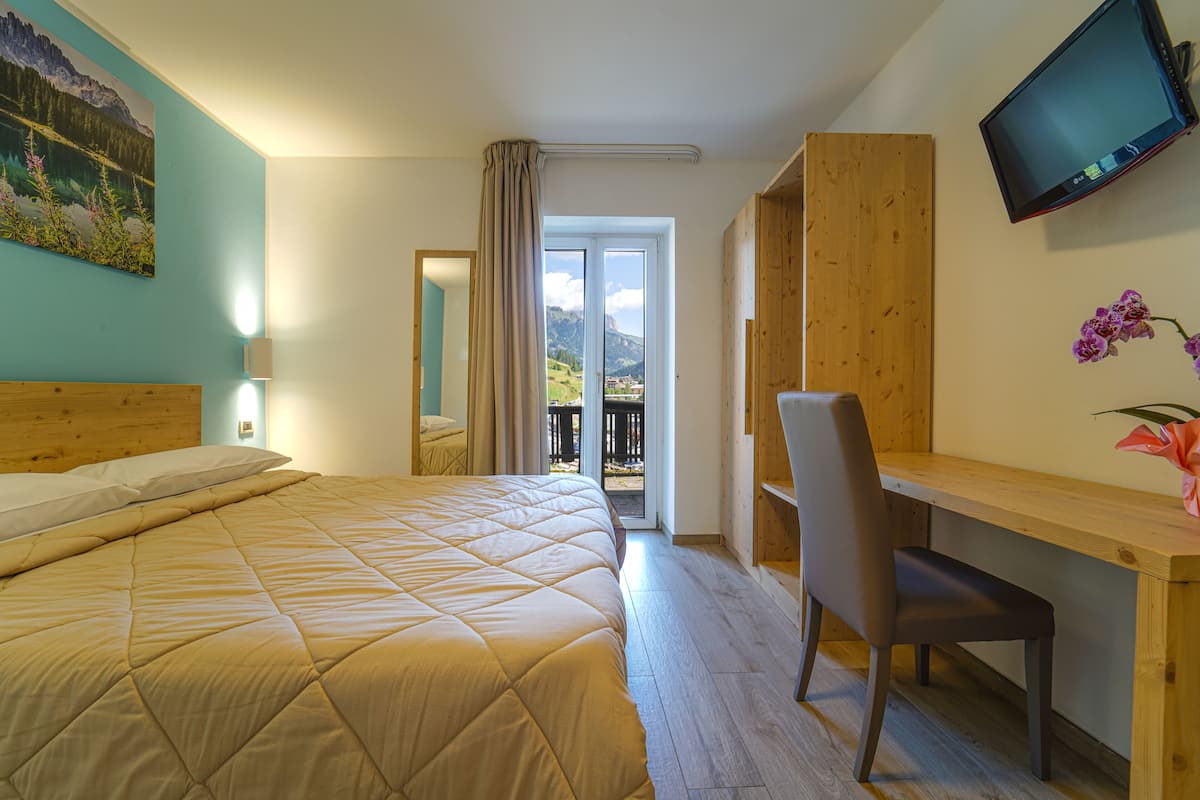 Een slaapkamer met een bed, bureau, stoel, televisie en uitzicht op de omgeving.