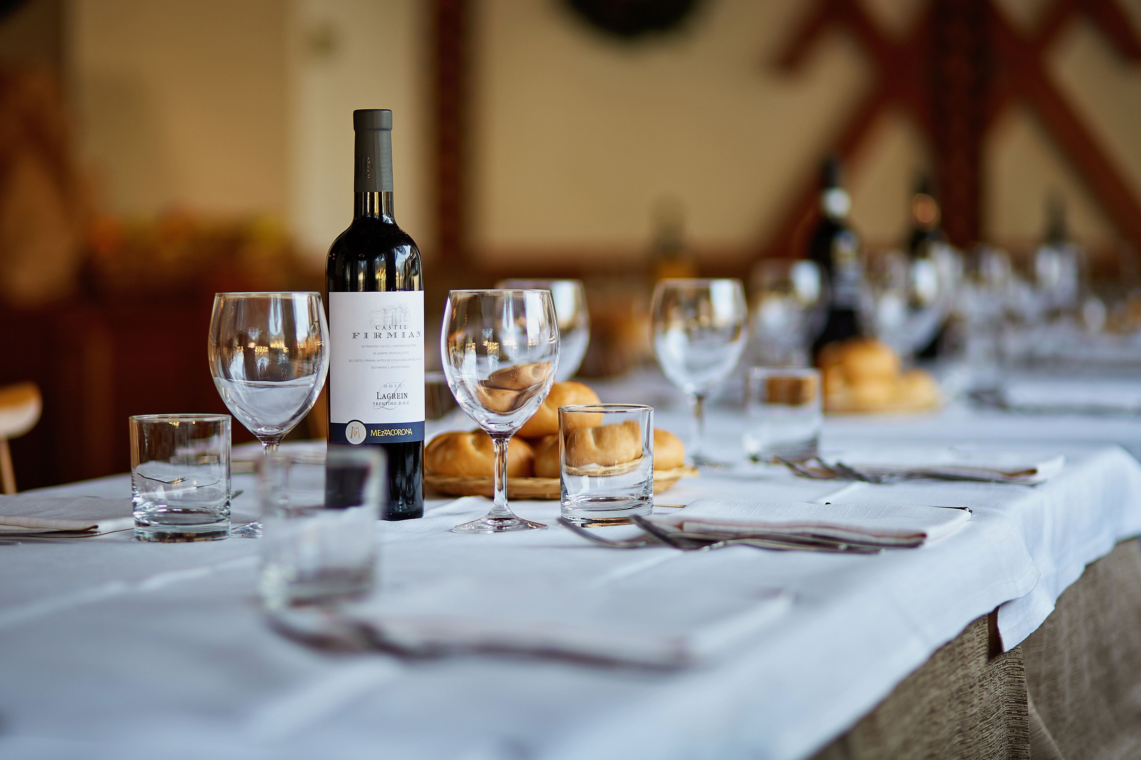 Een gedekte tafel voor een diner, met een fles Castello di Montalcino wijn, heldere glazen en een mand met brood.