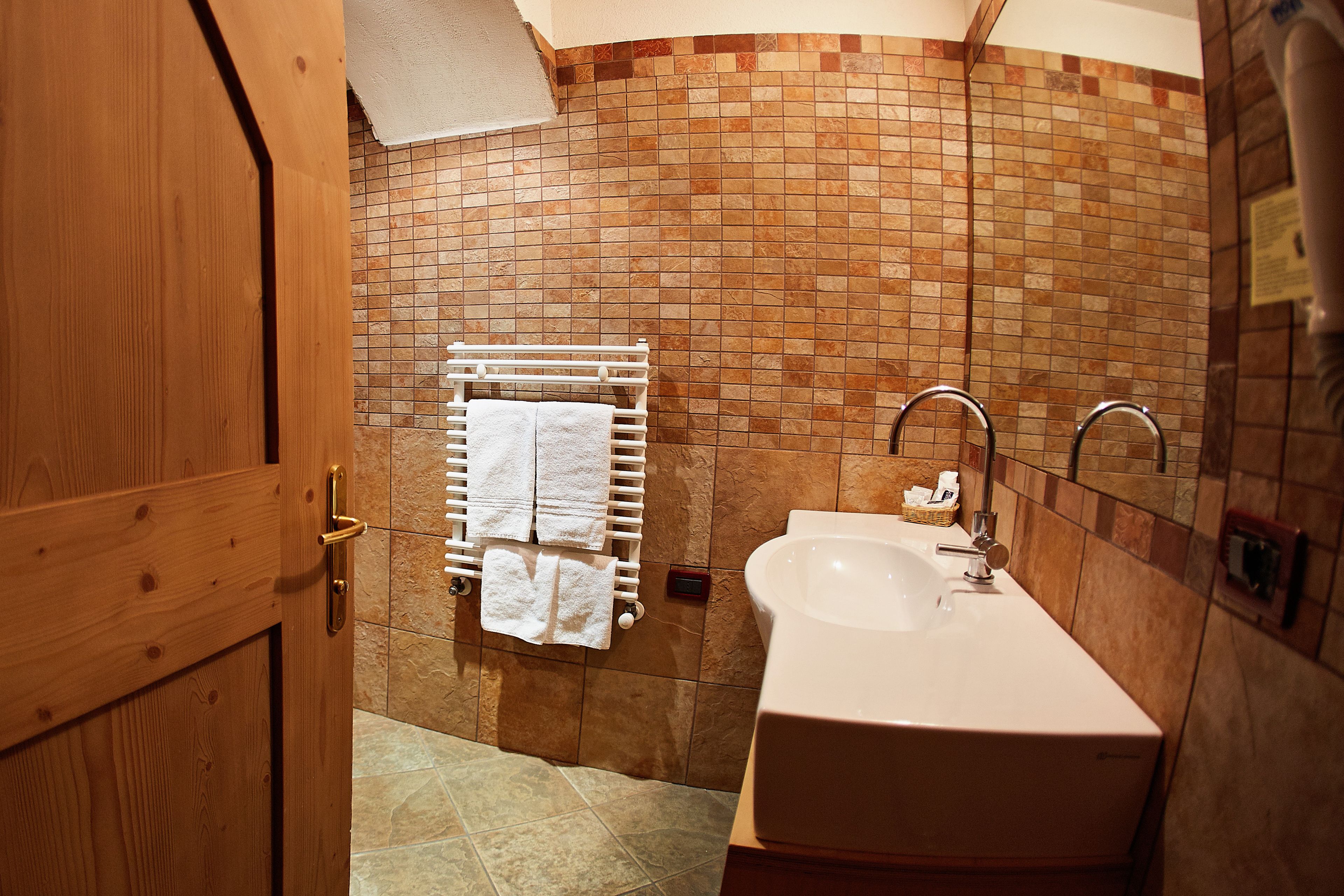 A bathroom with a tiled wall, a white sink, and a towel rack.