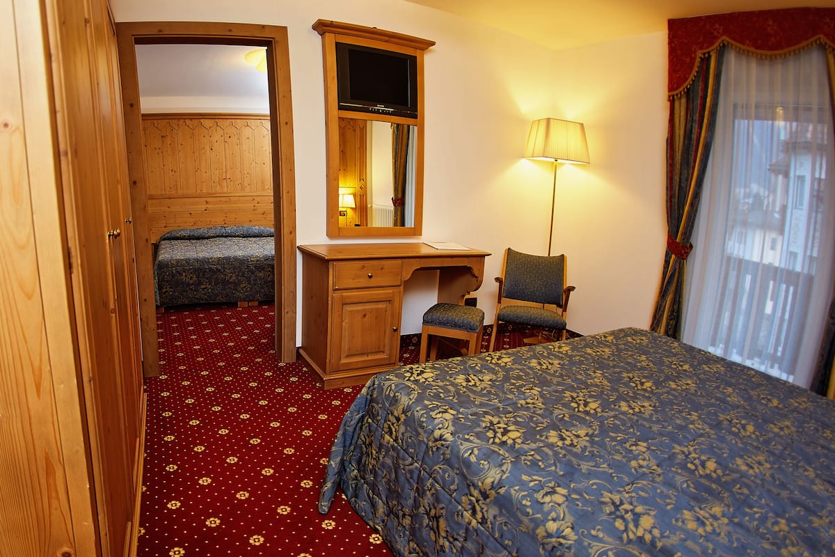 Een hotelkamer met een bed, een bureau, een stoel, een kledingkast en een spiegel.