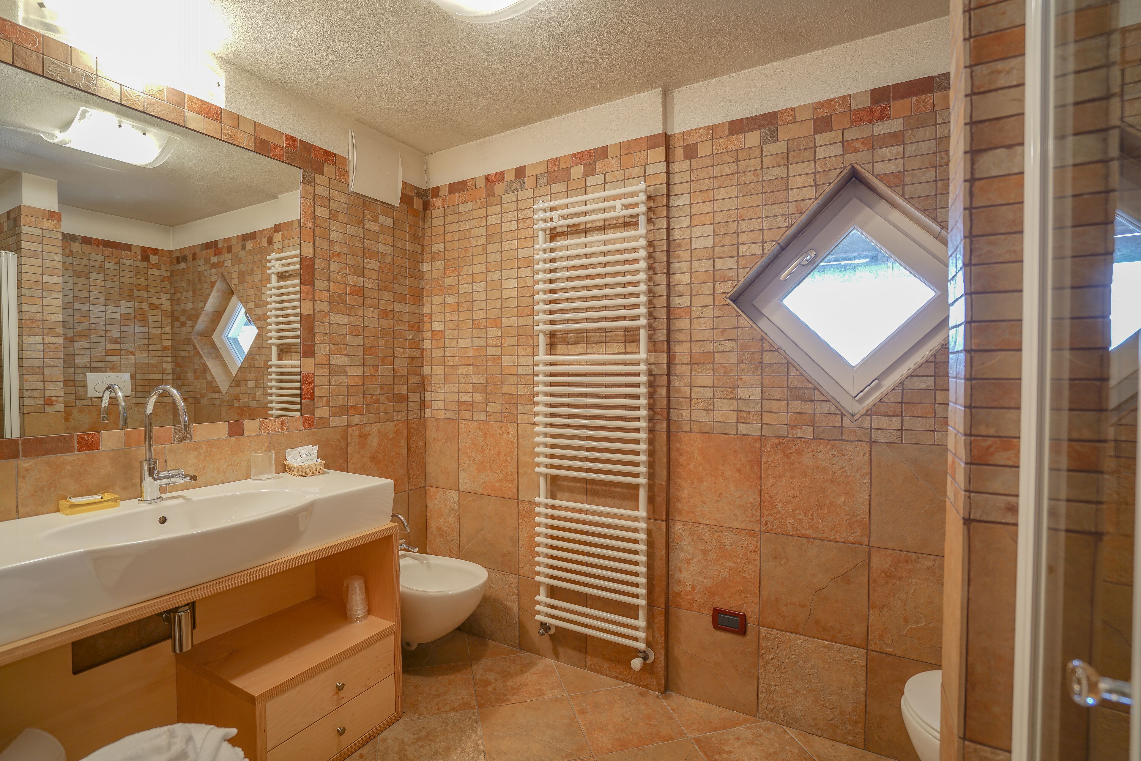 A bathroom with a sink, mirror, towel rack, and a window.