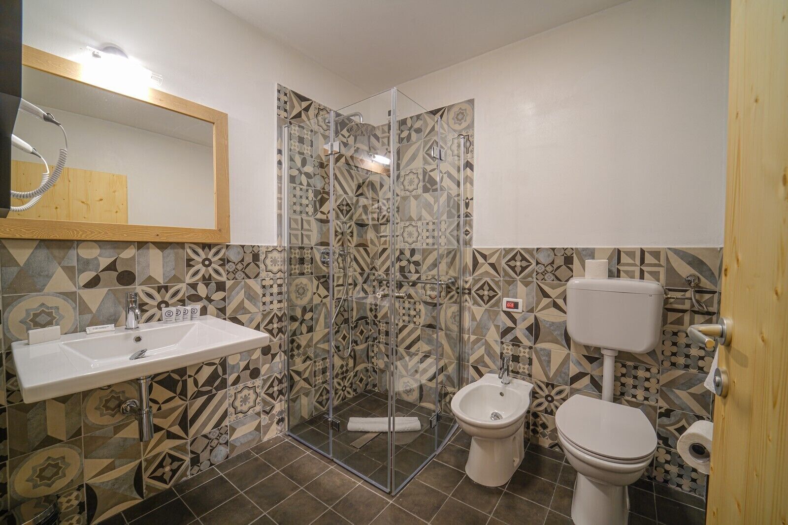 A bathroom with a shower, sink, toilet, and bidet.