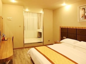 A hotel room with a bed, a desk, a mirror, and a painting on the wall.