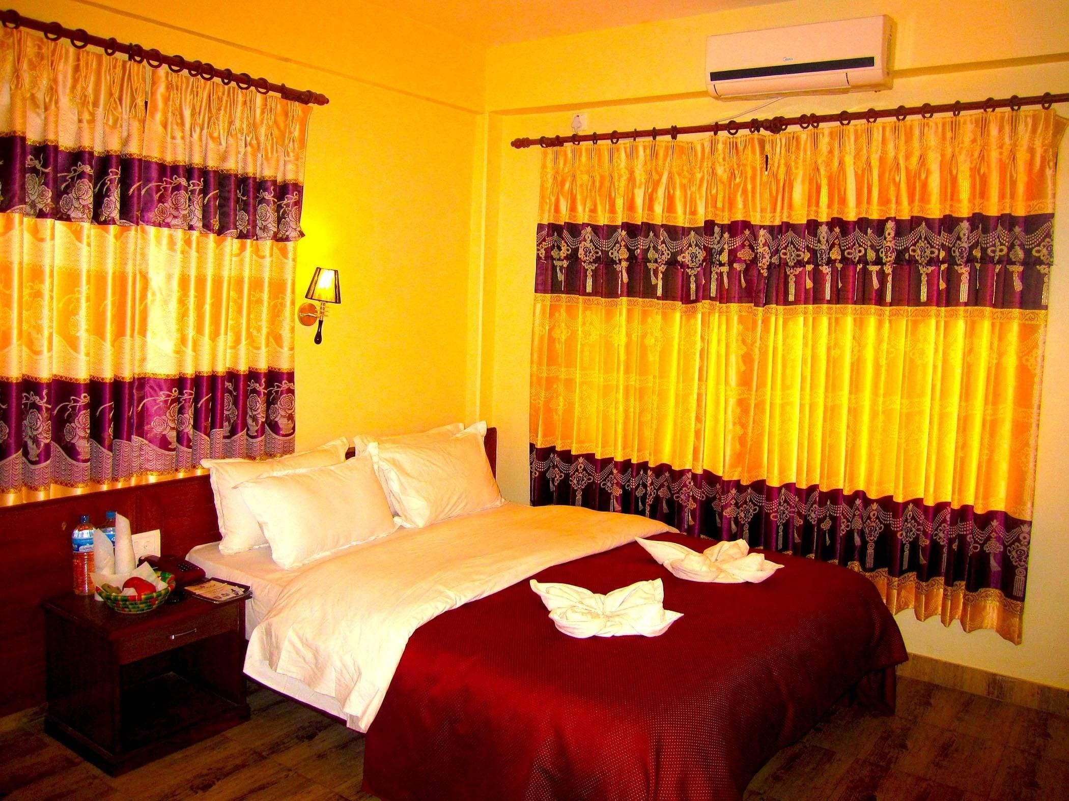 A hotel room with a bed, a nightstand, and curtains.