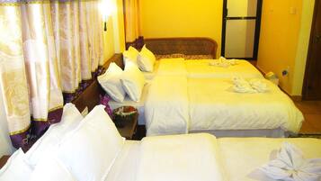 A hotel room with two beds, a large mirror, and a small table with a bowl and flowers.