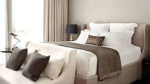 Habitación de hotel con cama, mesita de noche con lámpara y vistas al exterior.