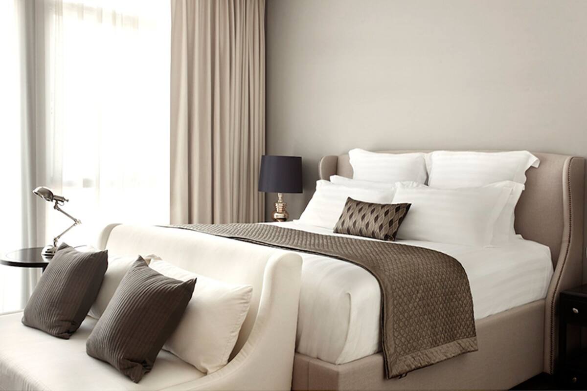 Ein Hotelzimmer mit Bett, Nachttisch mit Lampe und Blick ins Freie.