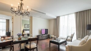 Una sala de estar moderna con comedor, un sofá, un televisor y una araña.