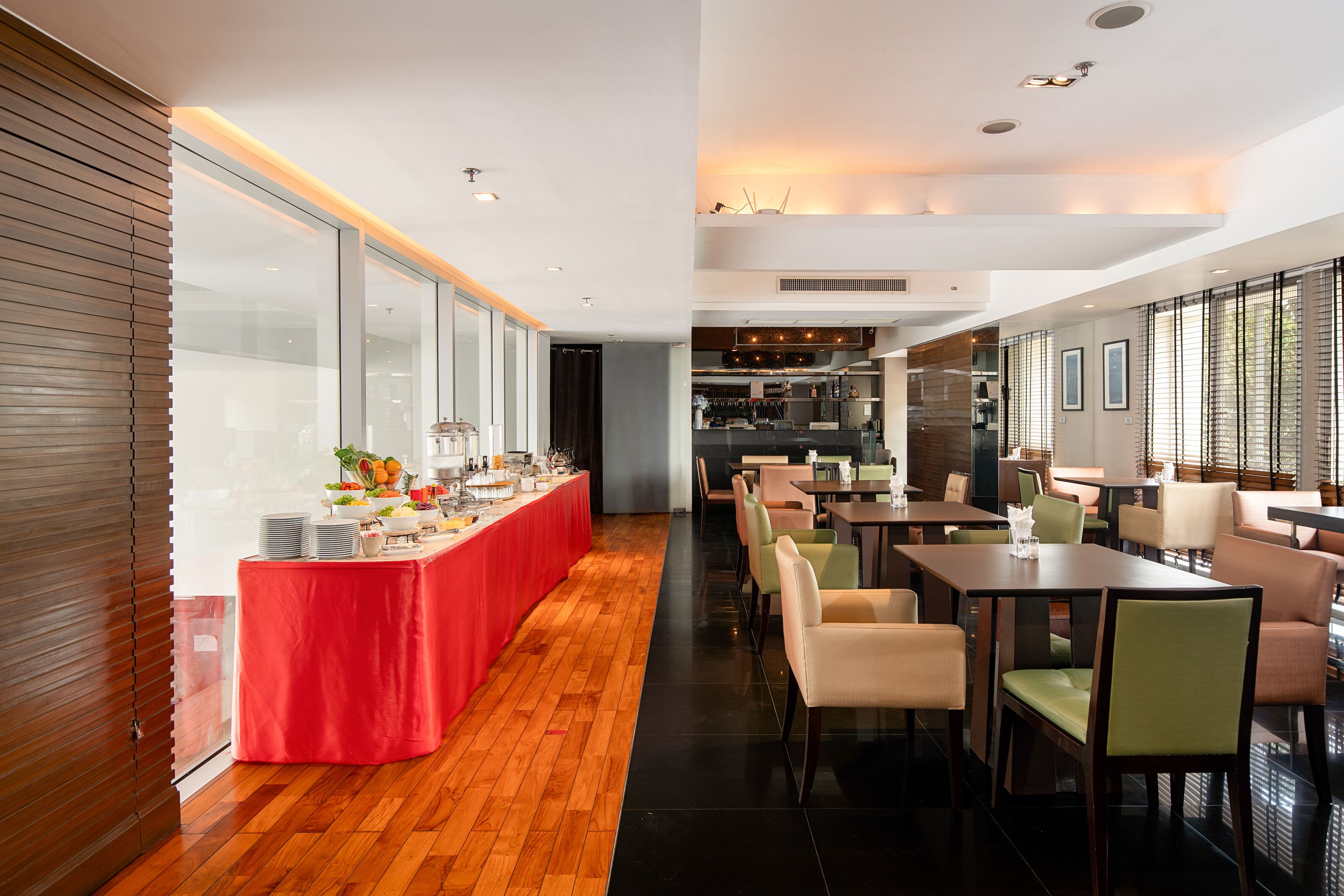 Een moderne hotel eetruimte met een lange balie, meerdere tafels en stoelen.