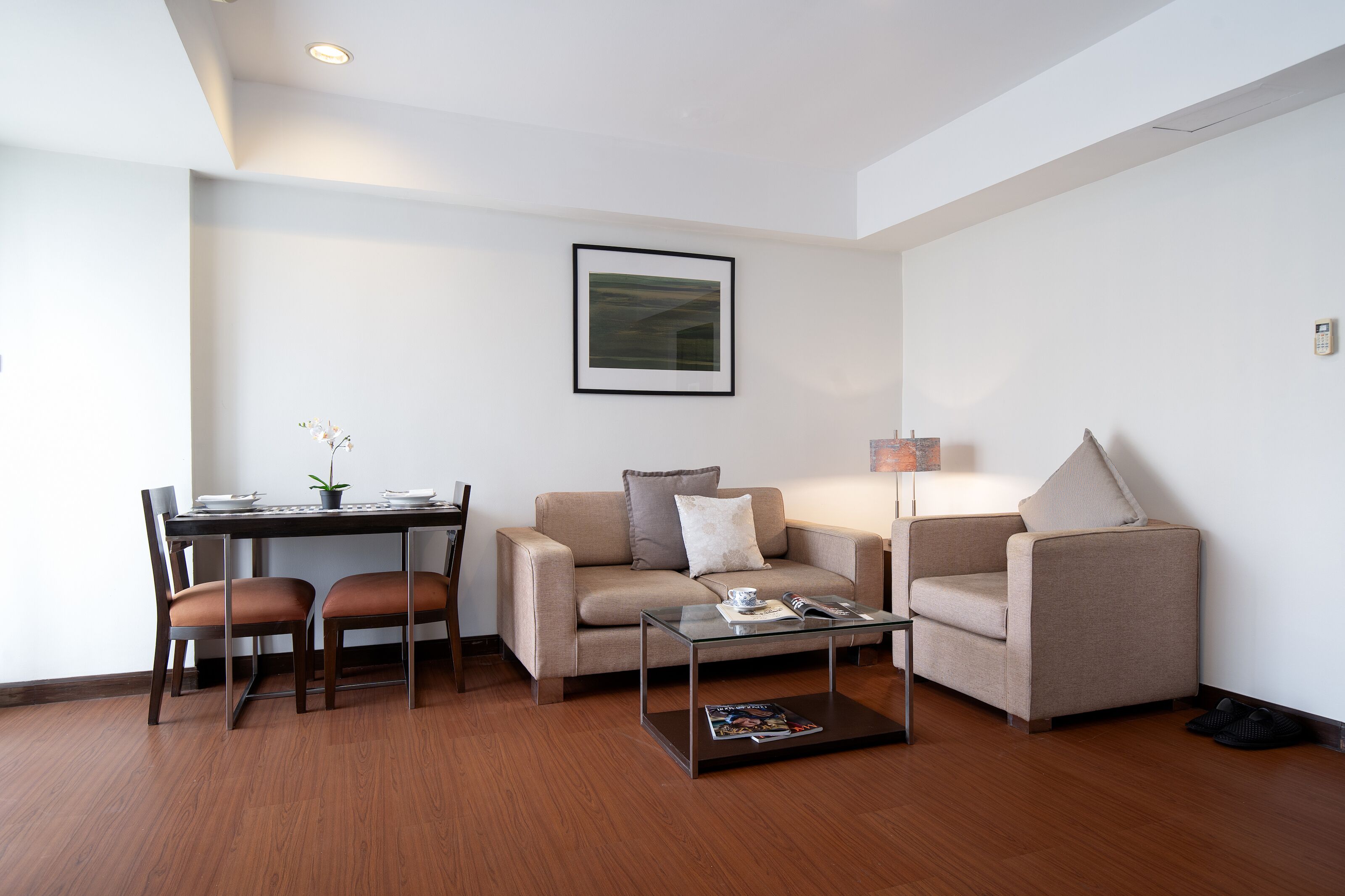 A modern living room with a sofa, armchair, coffee table, and dining area.