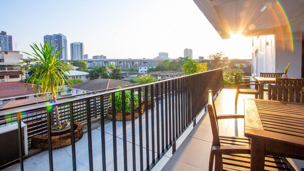 Un balcon donnant sur le paysage urbain, une table en bois et des chaises.