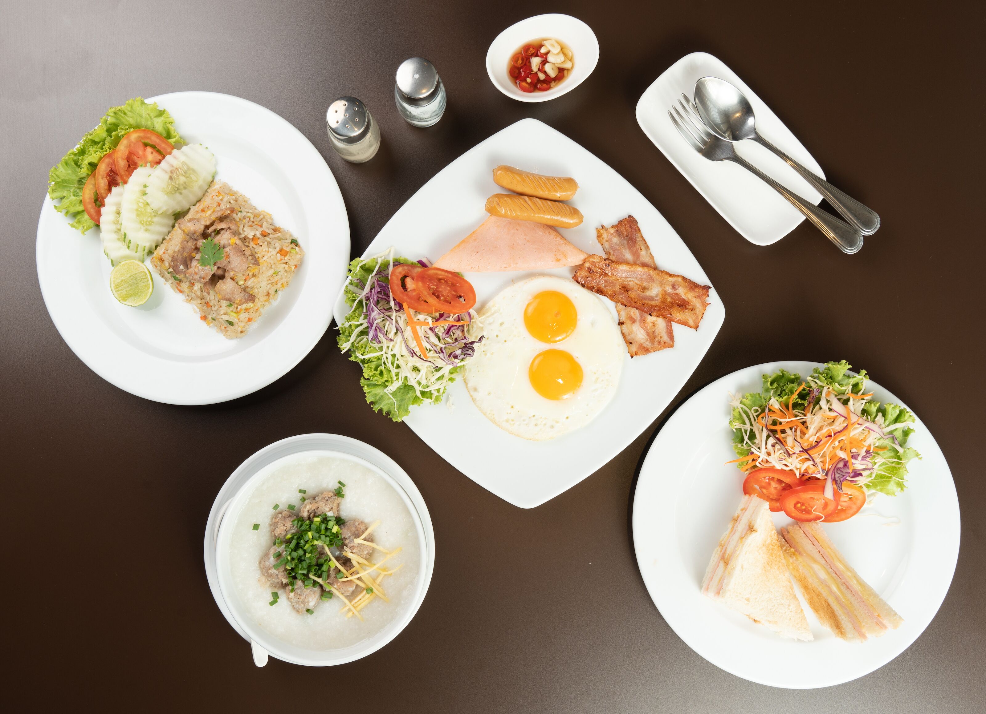 A table with various dishes including fried rice, eggs, bacon, and a salad.
