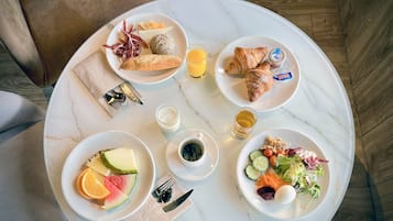A breakfast setting with plates of food, croissants, and juice on a marble table.