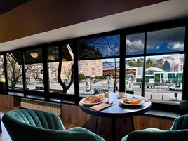 Zona pranzo con tavolo apparecchiato per due, ampie finestre con vista sulla città.