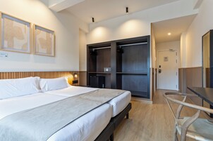 Ein modernes Hotelzimmer mit einem großen Bett, einem Schreibtisch und einem Kleiderschrank.