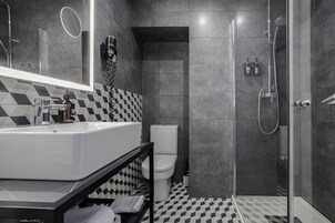 Ein modernes Badezimmer mit einem großen Spiegel, einem weißen Waschbecken, einer Toilette und einer Duschkabine.
