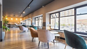 A modern interior with wooden flooring, large windows offering city views, and contemporary furniture. - Hotel Acta Madfor (Madrid)