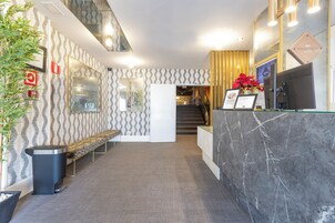 Zona de recepción con mostrador de mármol, un banco y una escalera que sube a un piso superior.