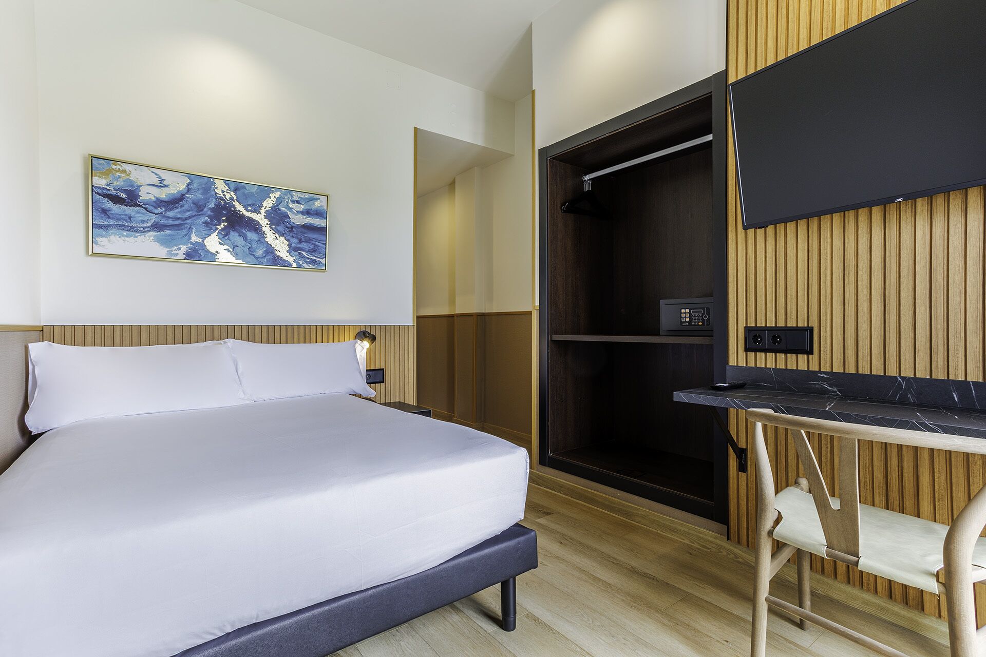 A modern hotel room with a bed, a desk, and a walk-in closet.