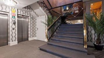Un vestíbulo de hotel con una escalera, ascensores y un cartel que dice "ENJOY OUR MADFOR LIVING AREA".