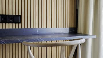 Una cocina con pared de listones de madera, encimera negra y taburete de madera.
