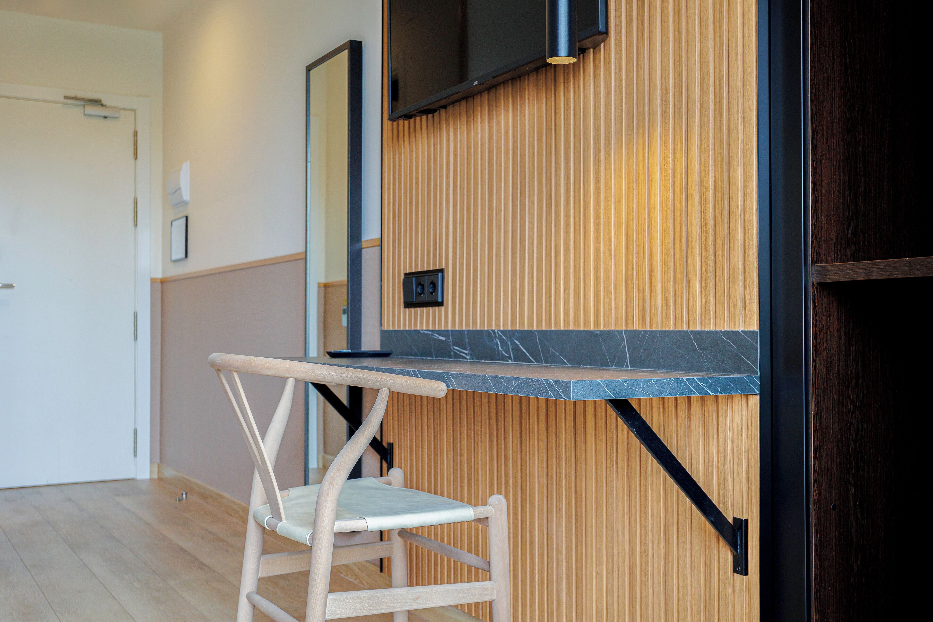 A modern room with a wooden wall, a black-framed TV, and a wooden chair.