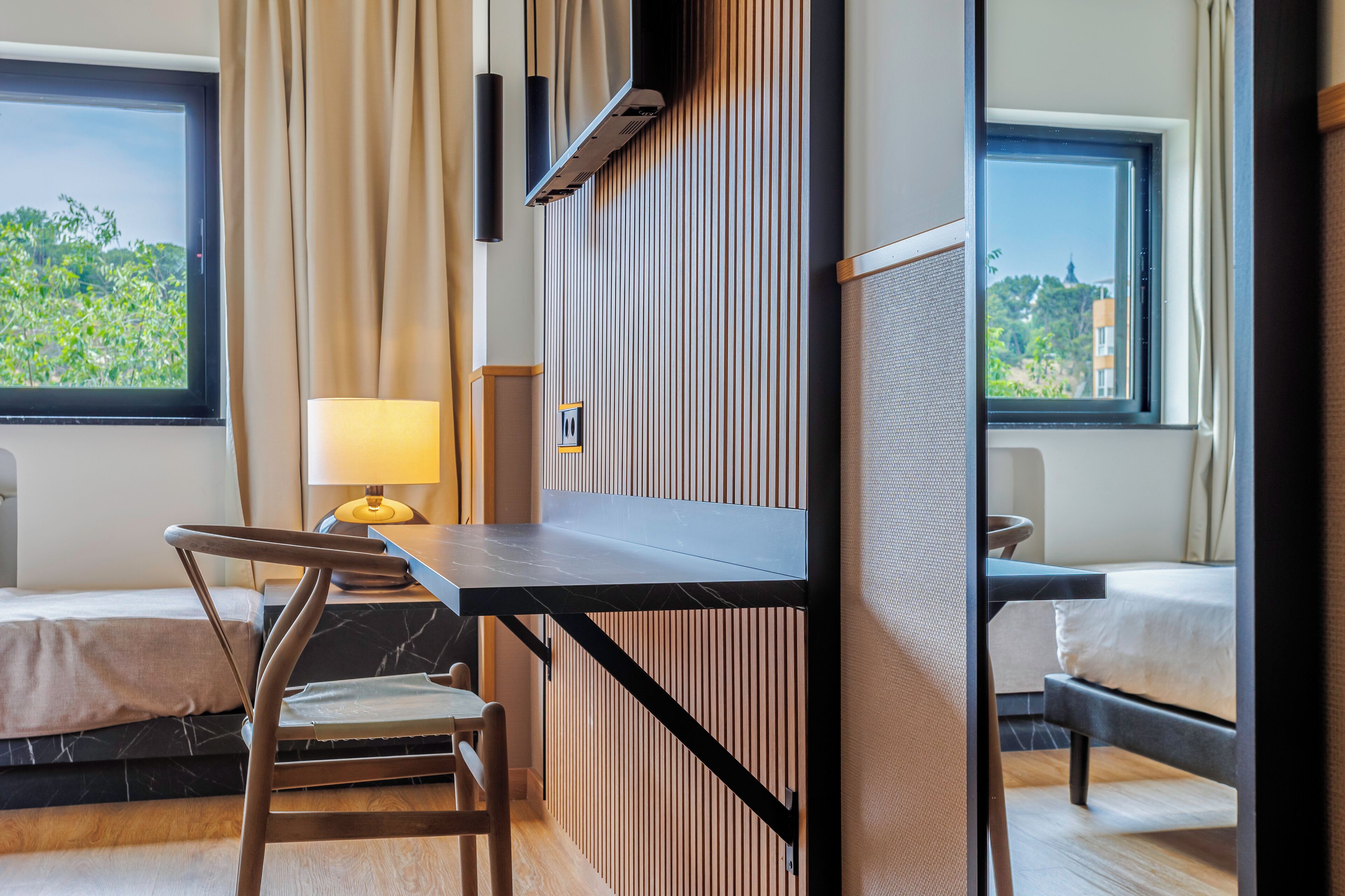 A modern hotel room with a desk, chair, and a bed.