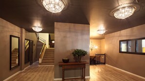 A spacious hallway with wooden flooring, a central console table with a plant, and a staircase leading to another level. - Hotel Acta Madfor (Madrid)