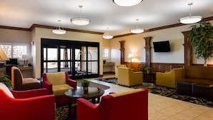 A hotel lobby with red and yellow seating, a television, and a large window with blinds. - Best Western Plus Landmark Hotel (Roosevelt)