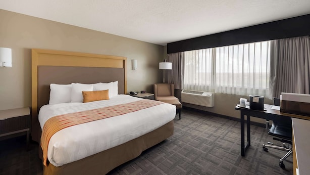 A hotel room with a large bed, a desk, an air conditioning unit, and a window with curtains. - Best Western Plus Landmark Hotel (Roosevelt)