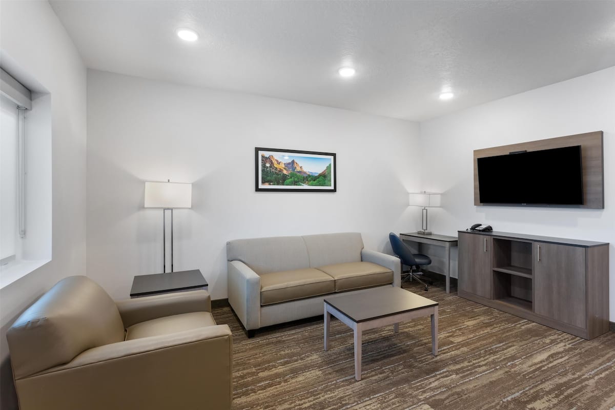 A modern living room with a sofa, armchair, coffee table, desk, and TV.