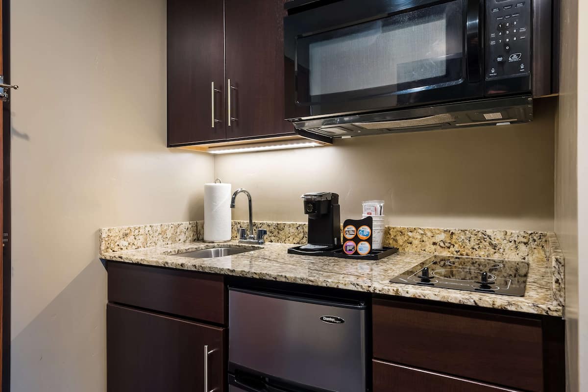 A kitchen with a microwave, coffee maker, and a sink.