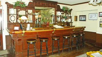 Un área de bar con taburetes de madera, un espejo y varios objetos decorativos.
