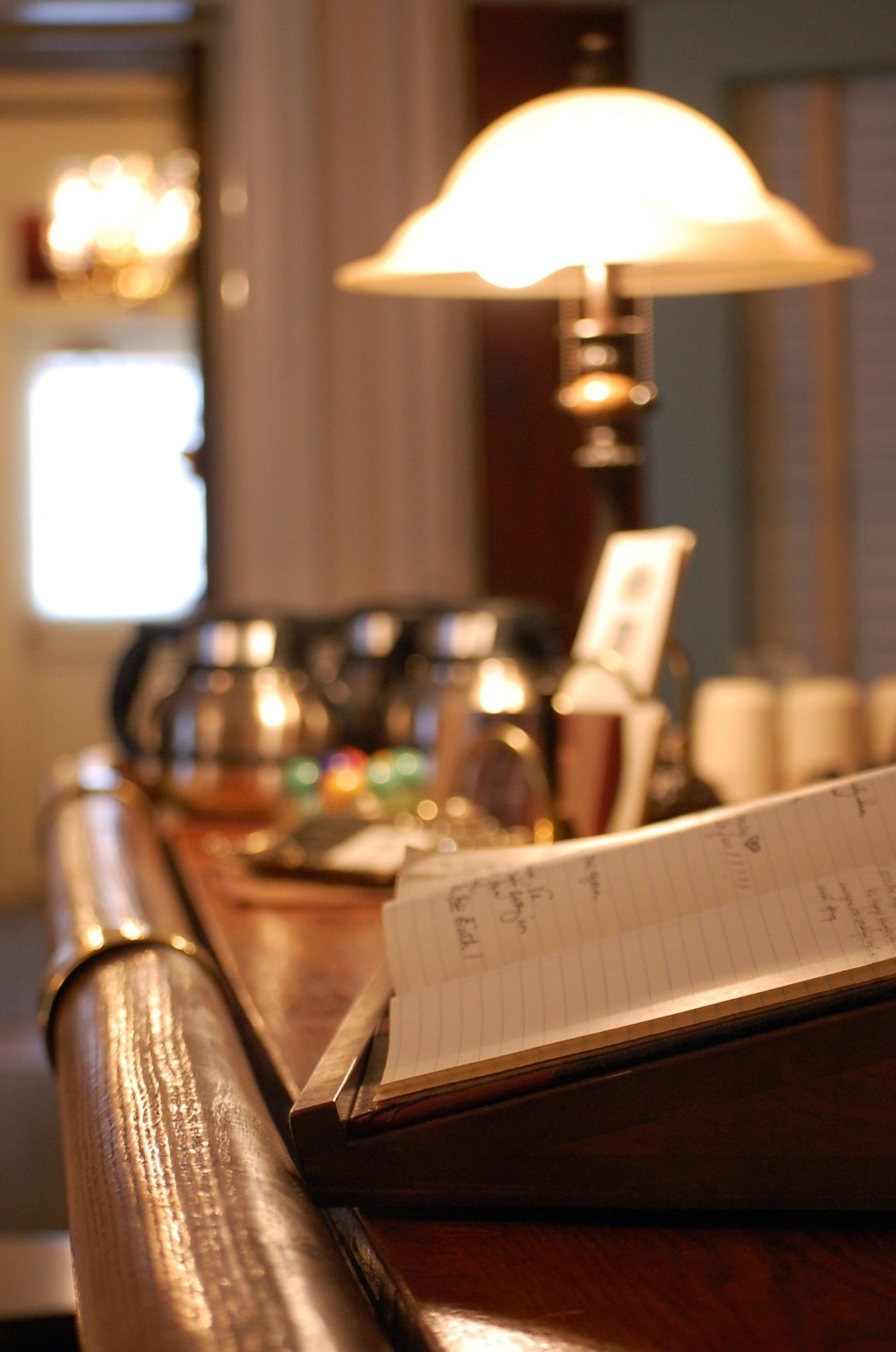 A wooden desk with a lamp, a notepad, and a framed picture.