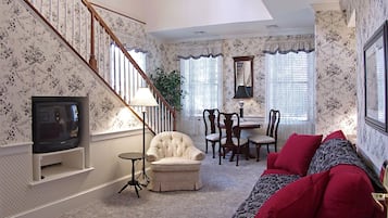A living room with a staircase, a television, a sofa, and a dining area.