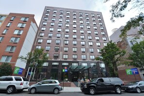A multi-story hotel with a modern design, featuring a prominent entrance with glass doors and a visible sign for Holiday Inn Express. - Holiday Inn Express New York - Manhattan West Side by IHG (New York)