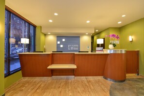 Un espace d’accueil comprenant un comptoir en bois, un banc et un panneau fixé au mur.
