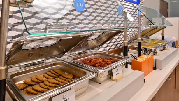 A buffet with labeled trays of turkey sausage, bacon, and cookies. - Holiday Inn Express New York - Manhattan West Side by IHG (New York)