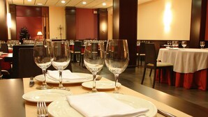 A dining table set with white plates, folded napkins, and empty wine glasses. - La Boroña (Gijon)