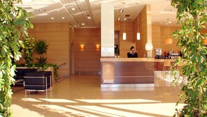 A hotel reception area with a modern design, featuring a reception desk, seating area, and potted plants. - La Boroña (Gijon)