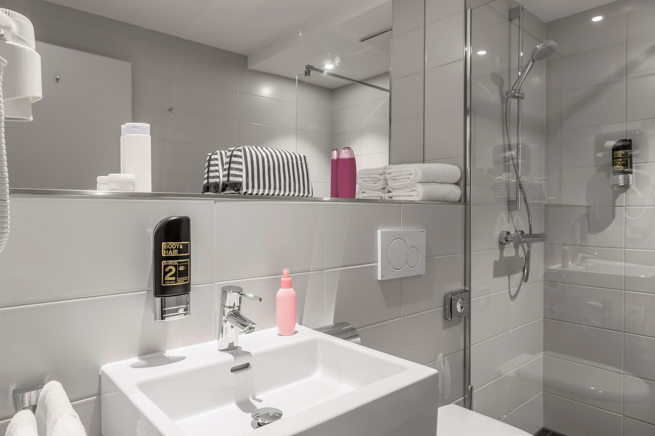 Un baño moderno con ducha de vidrio, lavabo blanco y espejo.