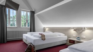 Een hotelkamer met een groot bed, een nachtkastje, gordijnen, een radiator en een plafondlamp.