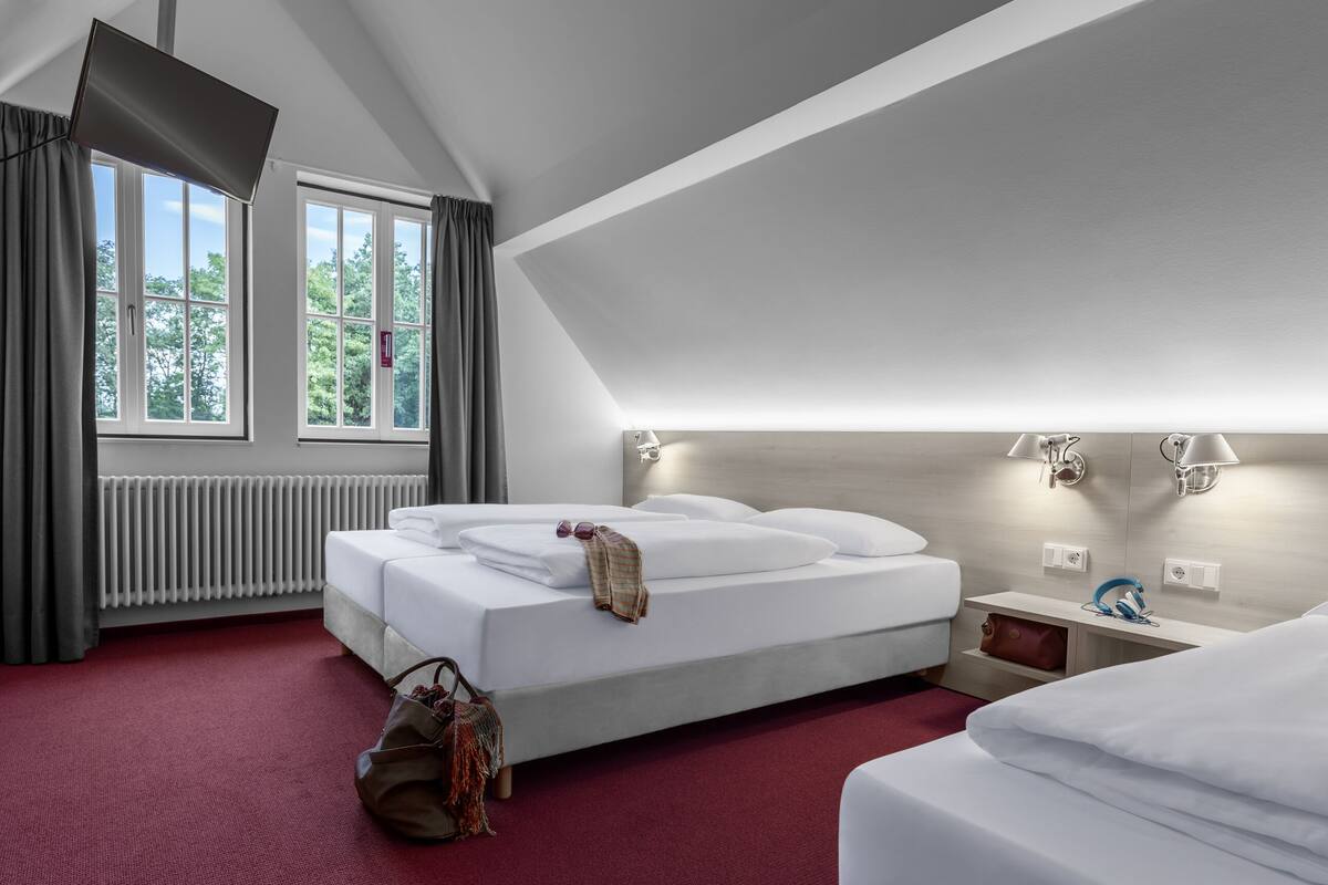 Een hotelkamer met een groot bed, een nachtkastje, gordijnen, een radiator en een plafondlamp.