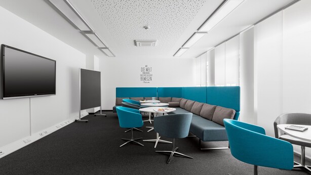 A modern conference room with a large flat-screen TV, a sofa, and several chairs. - Coffee Fellows Hotel Siegburg West (Siegburg)