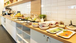 A buffet setup with various food items and utensils. - Coffee Fellows Hotel Siegburg West (Siegburg)