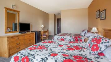 A hotel room with two beds, a wooden dresser, a television, and a desk with a chair.